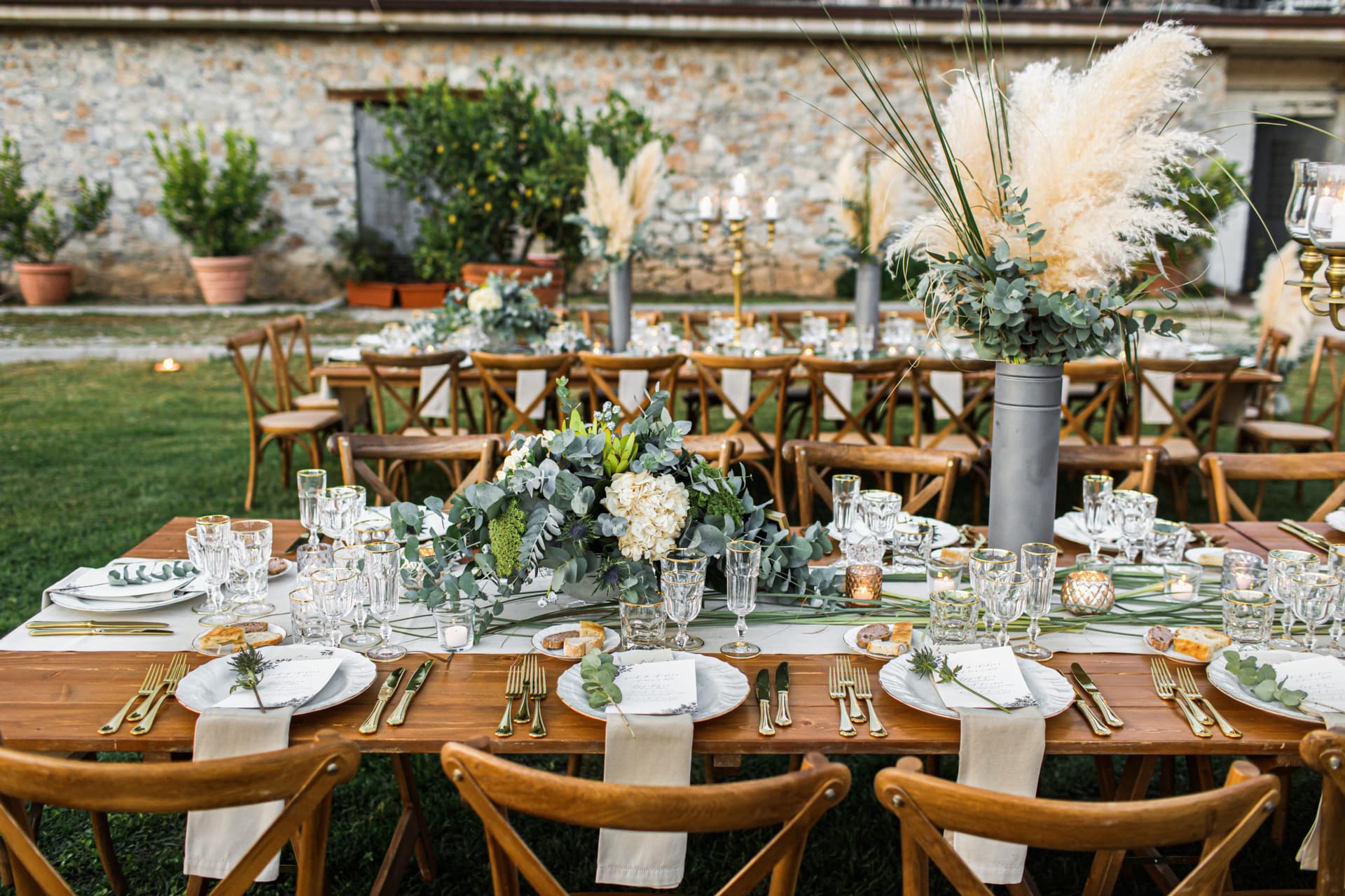 Long-table estate reception set under pampas grass arrangements — exemplifying The Luxe Collective's signature design aesthetic
